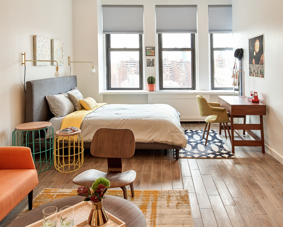 Inspiration for a small midcentury bedroom in New York with white walls, light hardwood floors and brown floor.