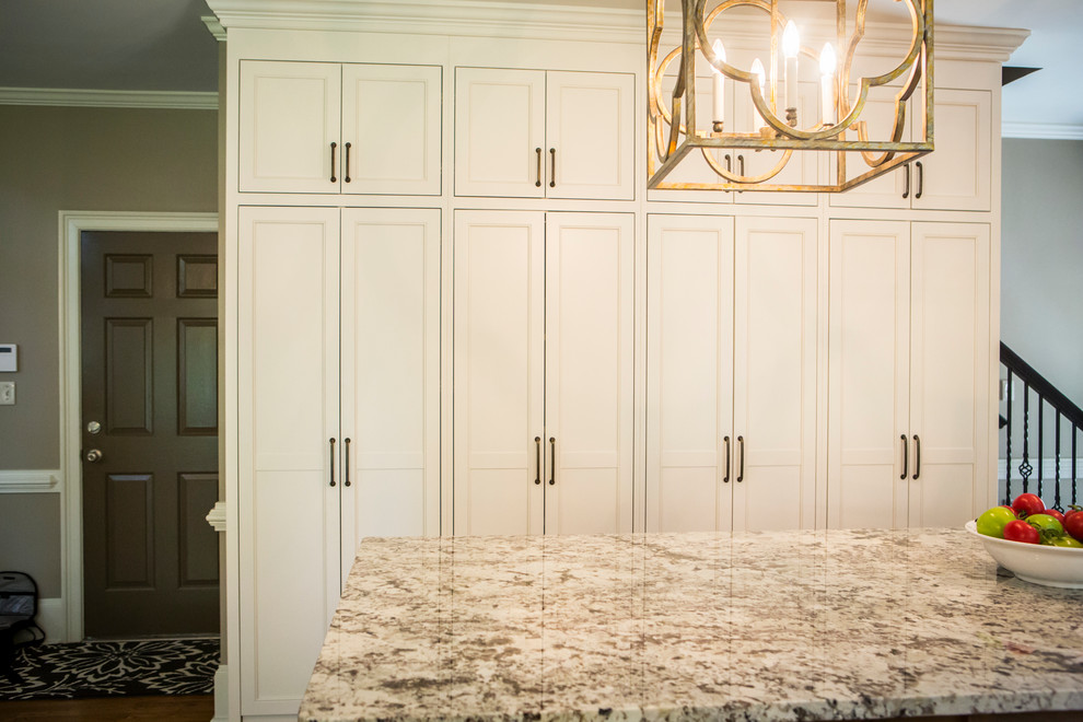Inspiration for a large transitional l-shaped medium tone wood floor eat-in kitchen remodel in Atlanta with a farmhouse sink, recessed-panel cabinets, white cabinets, granite countertops, gray backsplash, glass tile backsplash, stainless steel appliances and an island