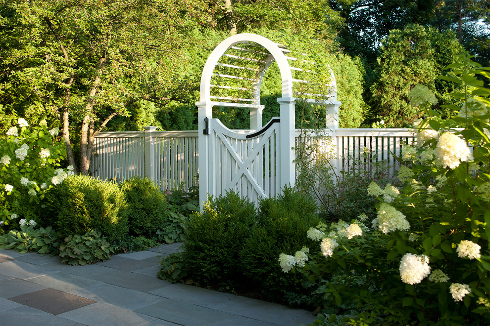 Large traditional backyard shaded formal garden in Chicago with natural stone pavers.