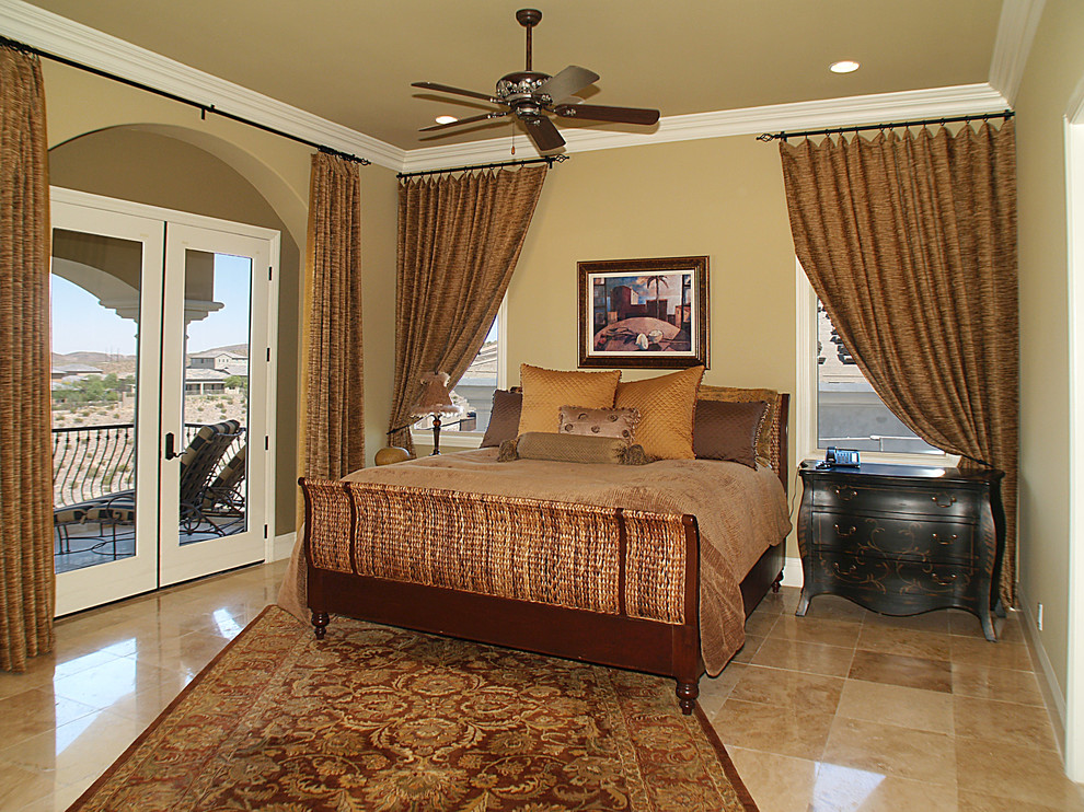 This is an example of an expansive mediterranean guest bedroom in Las Vegas with beige walls, brick floors, beige floor and vaulted.