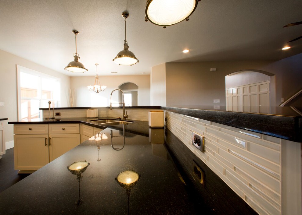 Home design - transitional porcelain tile home design idea in Austin with an undermount sink, shaker cabinets, white cabinets, granite countertops, white backsplash, glass sheet backsplash, stainless steel appliances and an island