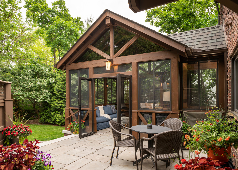 This is an example of a small traditional backyard screened-in verandah in Detroit with natural stone pavers and a roof extension.