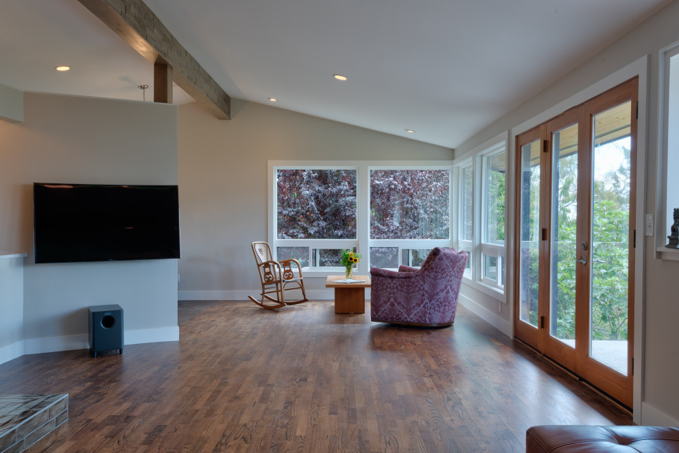 Photo of a mid-sized midcentury open concept living room in Seattle with grey walls, medium hardwood floors, a wall-mounted tv and exposed beam.