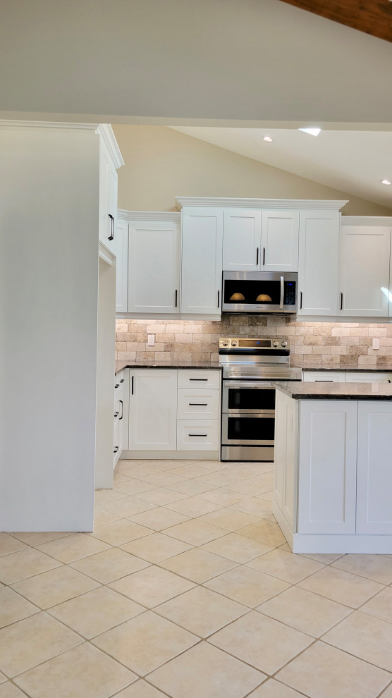 Transitional u-shaped open concept kitchen photo with an undermount sink, recessed-panel cabinets, white cabinets, multicolored backsplash, stone tile backsplash, stainless steel appliances and a peninsula