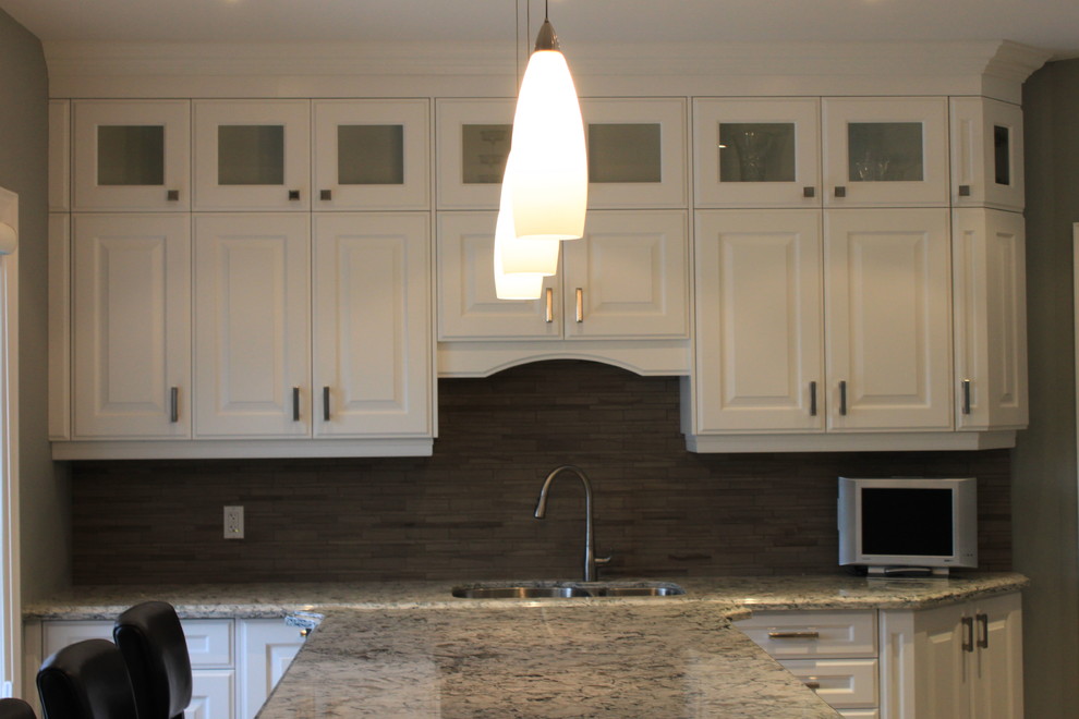 Example of a mid-sized transitional l-shaped porcelain tile and beige floor open concept kitchen design in Toronto with an undermount sink, raised-panel cabinets, white cabinets, granite countertops, beige backsplash, matchstick tile backsplash, stainless steel appliances, an island and beige countertops