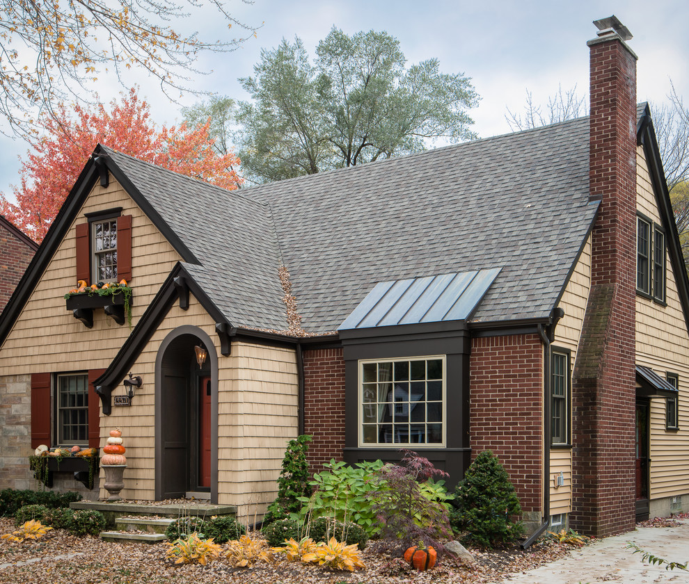 Small traditional two-storey brick beige house exterior in Detroit with a gable roof and a shingle roof.