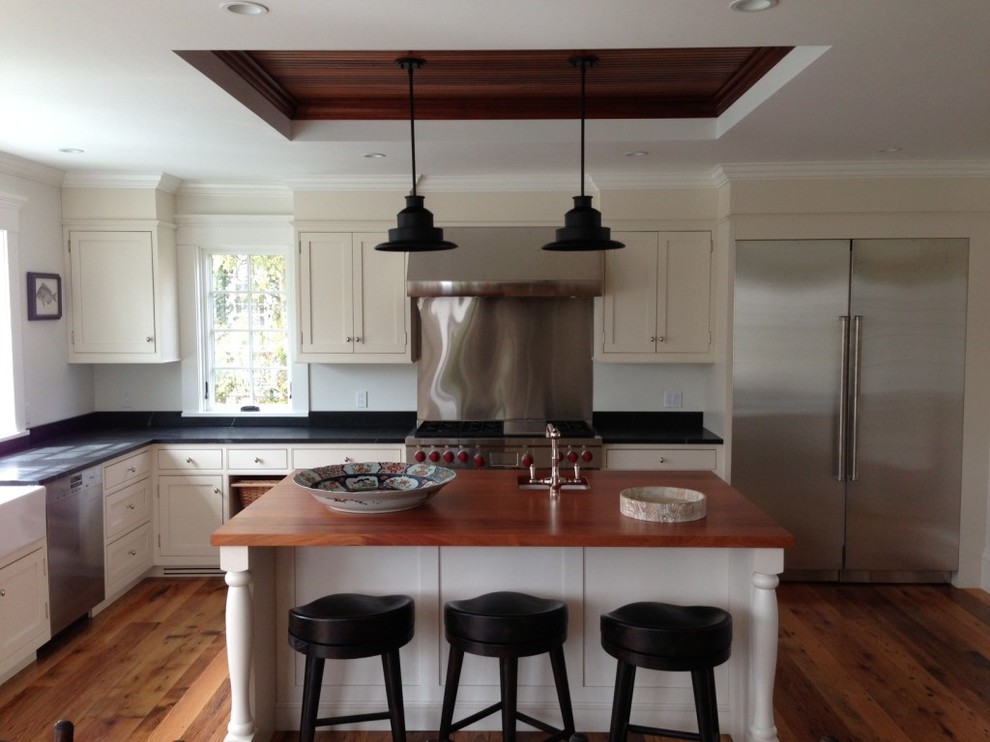 Mid-sized transitional l-shaped eat-in kitchen in Boston with a farmhouse sink, beaded inset cabinets, beige cabinets, quartz benchtops, metallic splashback, metal splashback, stainless steel appliances, medium hardwood floors, with island and brown floor.