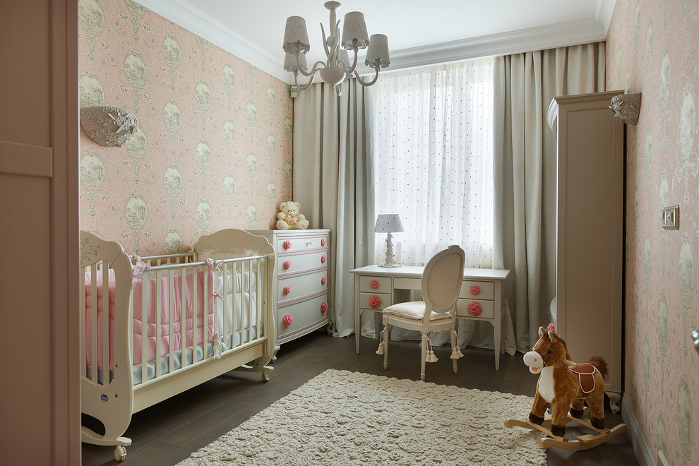This is an example of a traditional nursery for girls in London with pink walls, dark hardwood floors and brown floor.