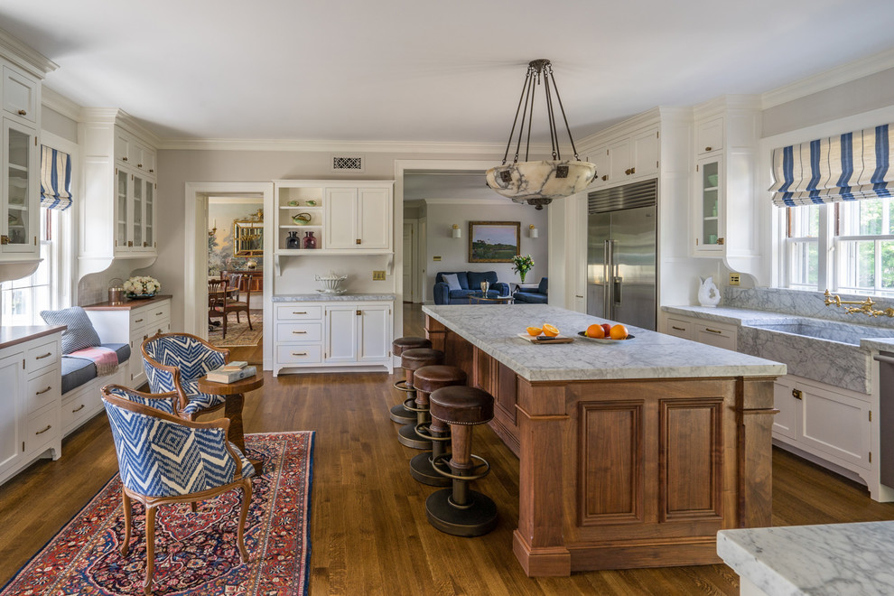 Elegant medium tone wood floor kitchen photo in Boston with a farmhouse sink, shaker cabinets, marble countertops, stainless steel appliances and an island