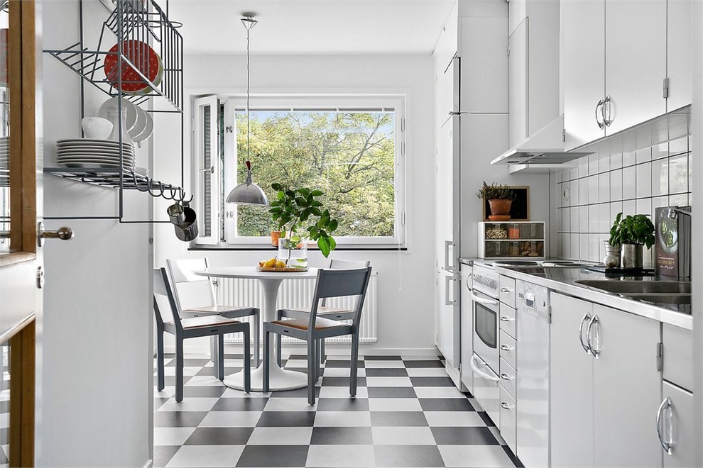 Design ideas for a mid-sized transitional single-wall eat-in kitchen in Stockholm with a drop-in sink, flat-panel cabinets, white cabinets, white splashback, white appliances, no island, stainless steel benchtops, porcelain splashback and ceramic floors.