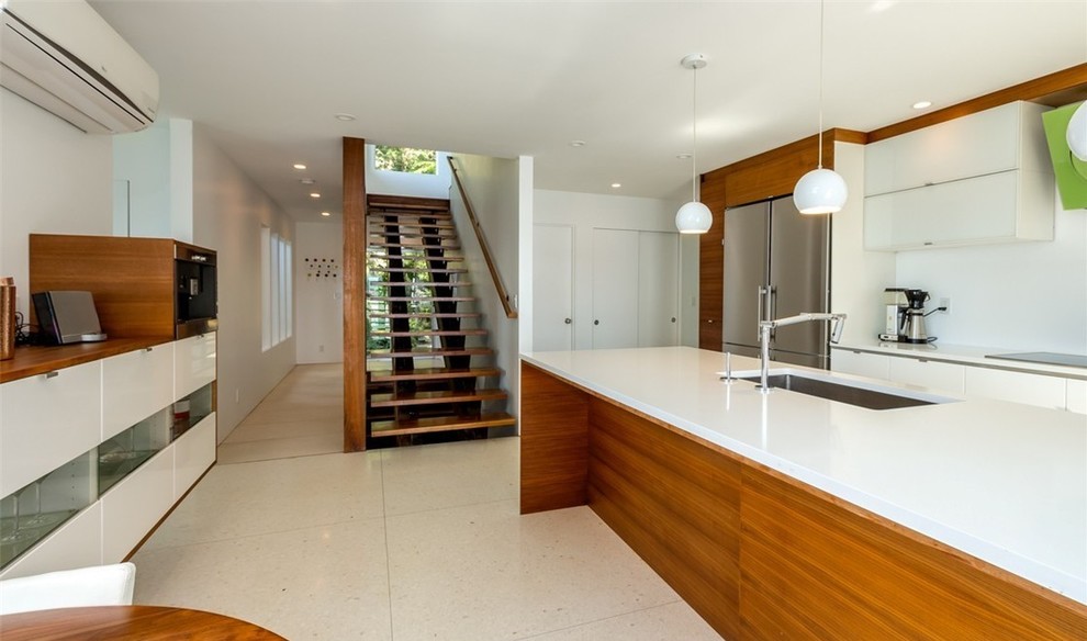 Inspiration for a large midcentury l-shaped separate kitchen in Seattle with an undermount sink, medium wood cabinets, solid surface benchtops, white splashback, stainless steel appliances, terrazzo floors, with island, white floor and flat-panel cabinets.