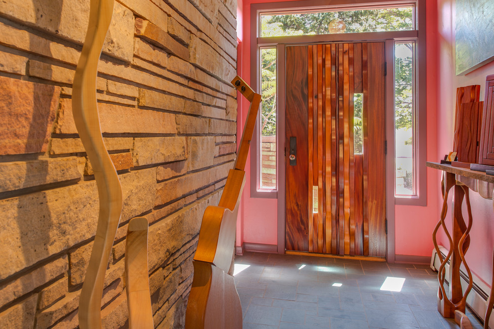 This is an example of a mid-sized contemporary foyer in Denver with pink walls, concrete floors, a single front door and a dark wood front door.