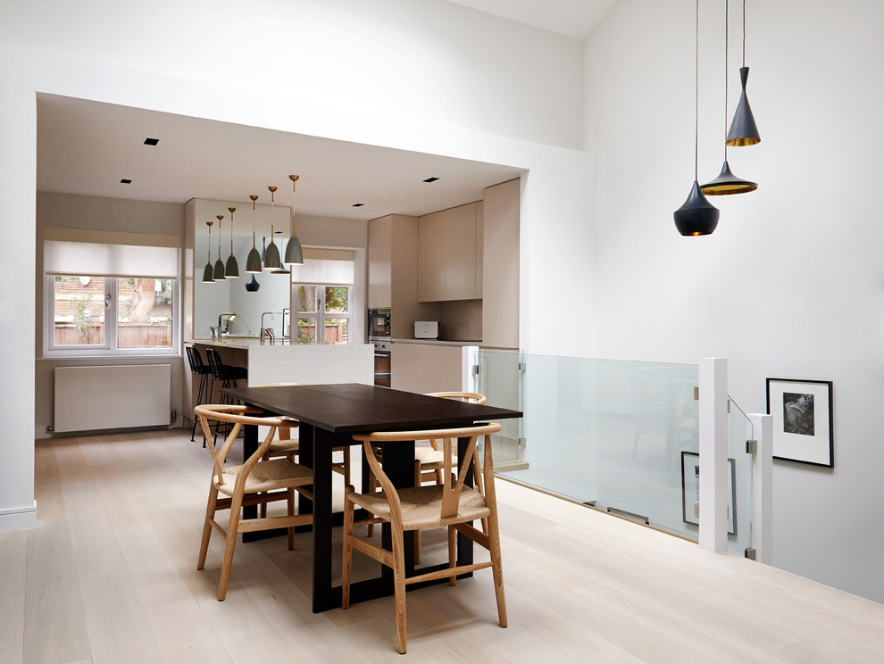 Contemporary open plan dining in London with grey walls, light hardwood floors and no fireplace.