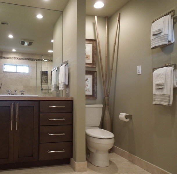 Design ideas for a mid-sized modern 3/4 bathroom in New Orleans with shaker cabinets, dark wood cabinets, an alcove shower, a two-piece toilet, brown walls, limestone floors, a drop-in sink, solid surface benchtops, beige floor, a hinged shower door and a drop-in tub.