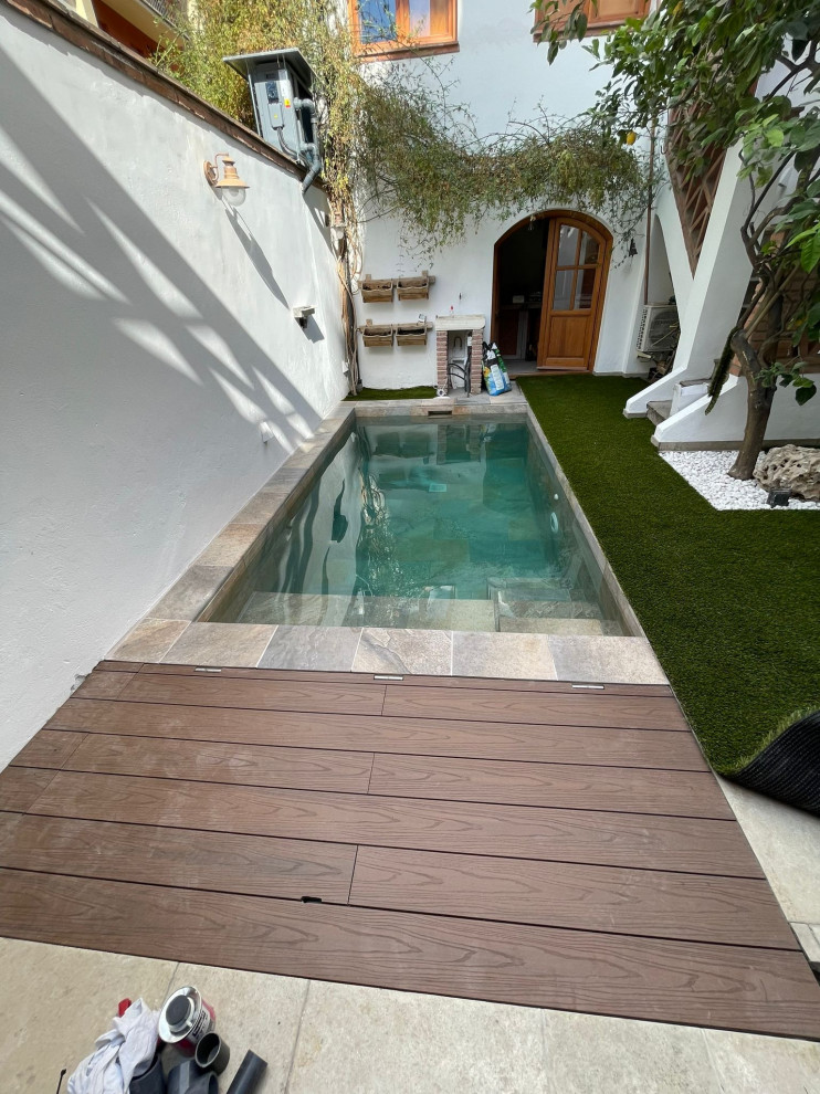 Ejemplo de casa de la piscina y piscina alargada minimalista pequeña rectangular en patio trasero con suelo de baldosas