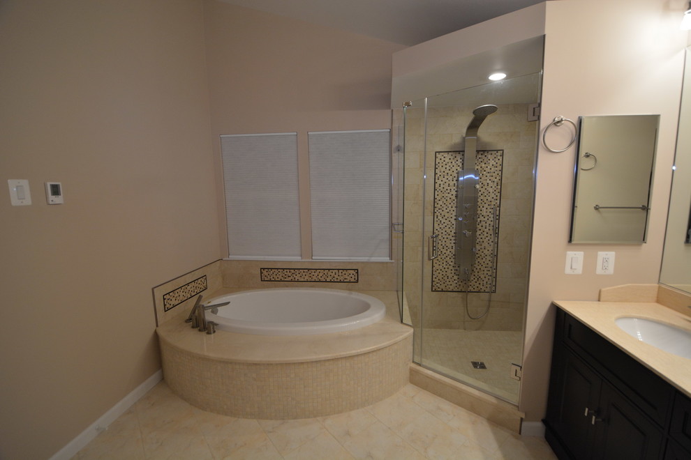 Example of a large transitional master beige tile and stone tile marble floor and beige floor drop-in bathtub design in Baltimore with dark wood cabinets, a two-piece toilet, beige walls, an undermount sink, beaded inset cabinets, solid surface countertops, a hinged shower door and beige countertops