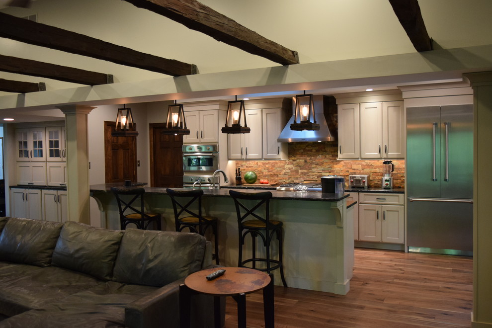 Large transitional galley medium tone wood floor kitchen photo with an undermount sink, recessed-panel cabinets, white cabinets, quartz countertops, multicolored backsplash, stone slab backsplash, stainless steel appliances and an island