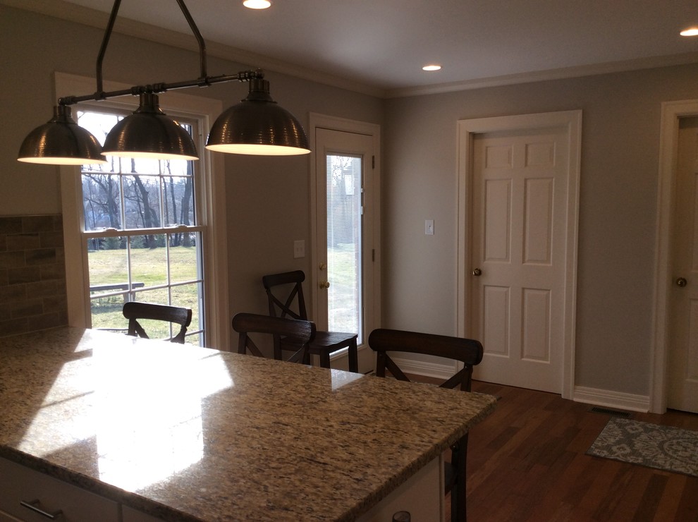 Inspiration for a transitional u-shaped medium tone wood floor kitchen remodel with an undermount sink, shaker cabinets, white cabinets, granite countertops, beige backsplash, subway tile backsplash, stainless steel appliances and a peninsula