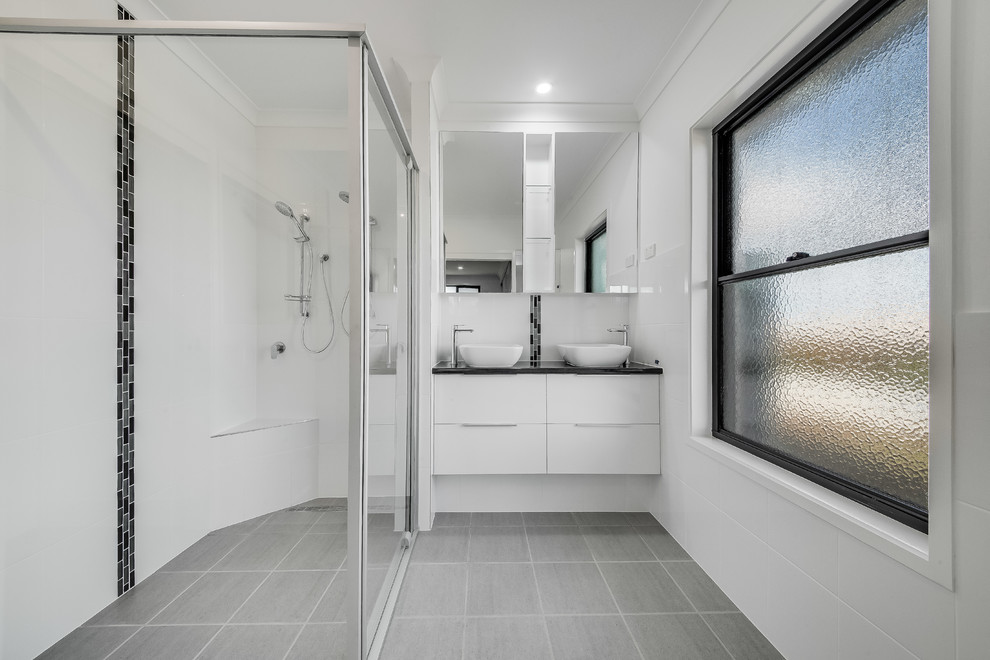 This is an example of a mid-sized contemporary bathroom in Other with flat-panel cabinets, white cabinets, black and white tile, ceramic tile, white walls, a vessel sink, grey floor, black benchtops, an alcove shower and a sliding shower screen.