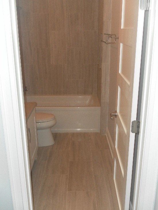 Example of a transitional beige tile alcove bathtub design in Chicago with white cabinets and white walls