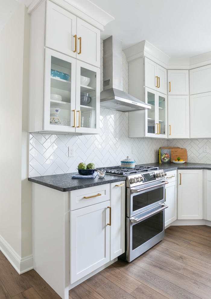 Inspiration for a large transitional l-shaped brown floor kitchen pantry remodel in Baltimore with a drop-in sink, shaker cabinets, white cabinets, quartz countertops, white backsplash, ceramic backsplash, stainless steel appliances, an island and white countertops