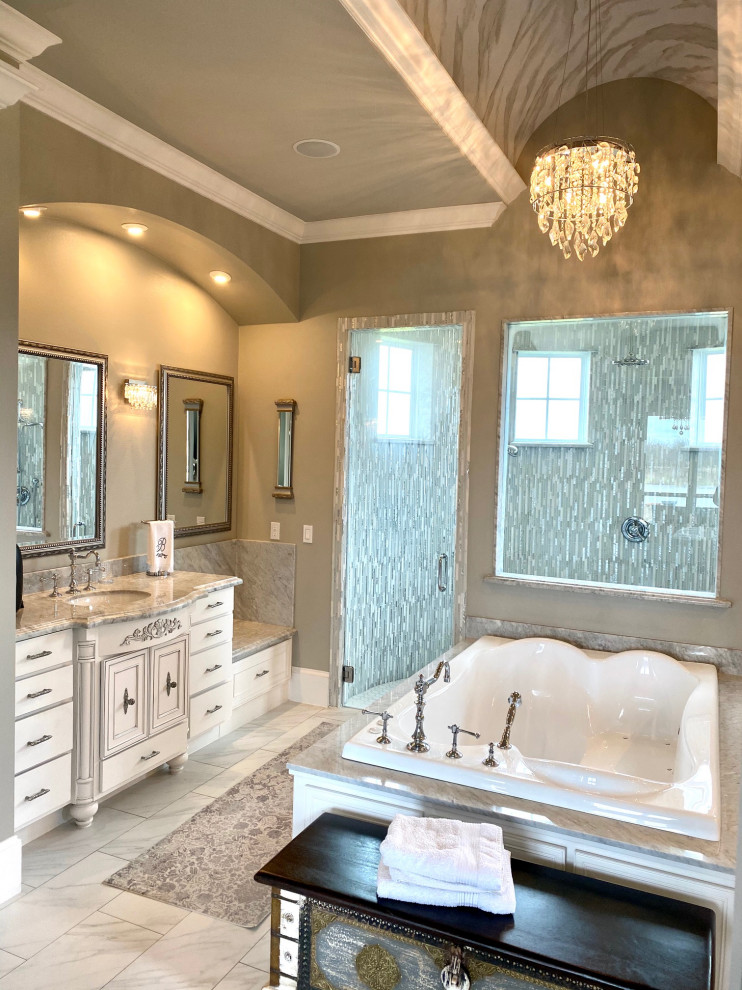Inspiration for a large master bathroom in Dallas with recessed-panel cabinets, distressed cabinets, a drop-in tub, a curbless shower, a two-piece toilet, gray tile, marble, grey walls, porcelain floors, an undermount sink, marble benchtops, white floor, a hinged shower door and grey benchtops.