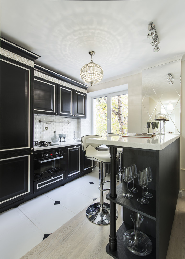 Photo of a traditional galley open plan kitchen in Moscow with raised-panel cabinets, black cabinets, white splashback, subway tile splashback, black appliances and a peninsula.