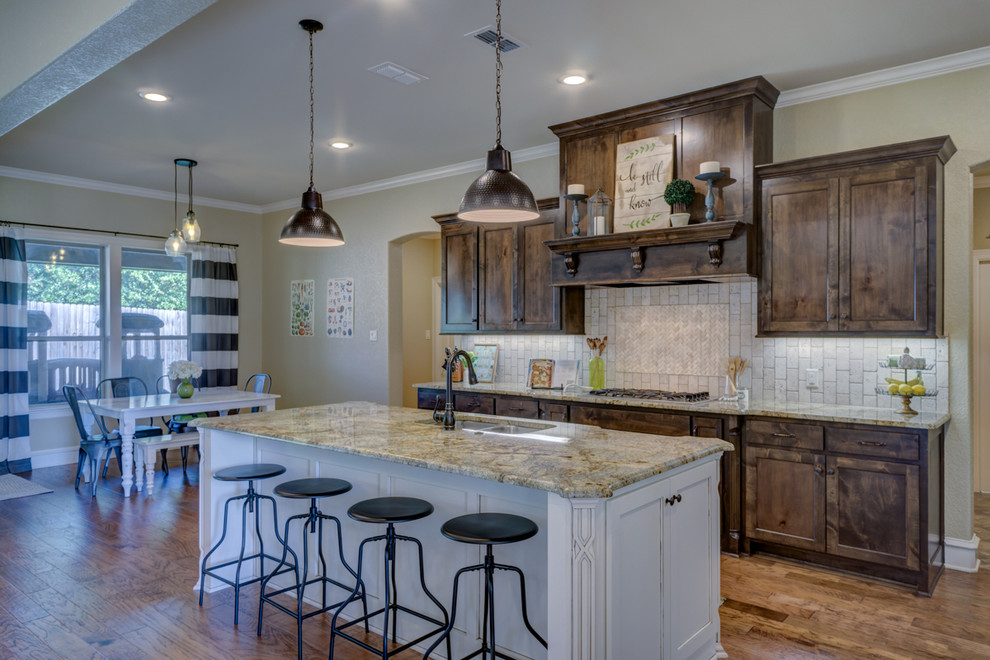 This is an example of a large traditional galley eat-in kitchen in Austin with an undermount sink, dark wood cabinets, granite benchtops, beige splashback, stone tile splashback, stainless steel appliances, medium hardwood floors, with island and shaker cabinets.
