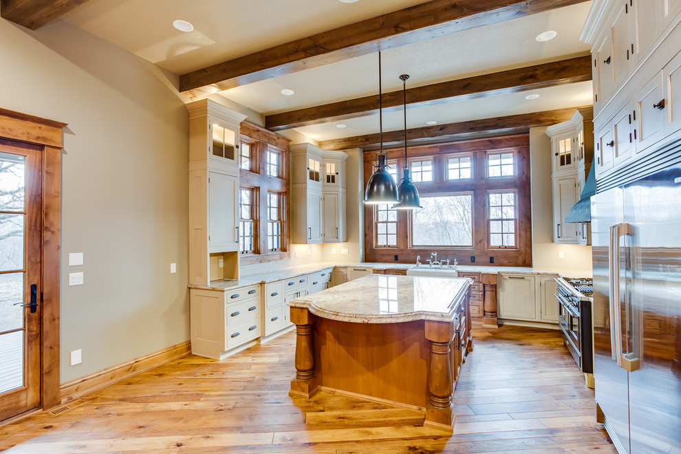 Example of a huge mountain style u-shaped medium tone wood floor eat-in kitchen design with a farmhouse sink, beaded inset cabinets, beige cabinets, granite countertops, beige backsplash, mosaic tile backsplash, stainless steel appliances and an island
