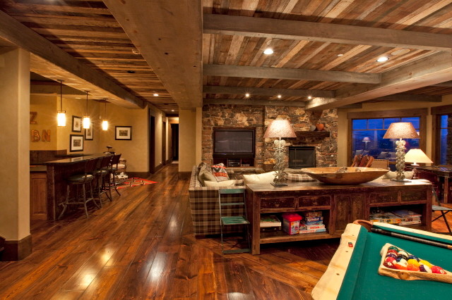 Inspiration for a large country open concept family room in Salt Lake City with a game room, beige walls, medium hardwood floors, a standard fireplace, a stone fireplace surround and a built-in media wall.