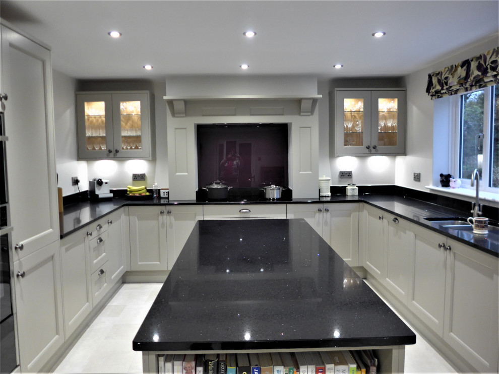 Design ideas for a large traditional u-shaped eat-in kitchen in West Midlands with shaker cabinets, quartzite benchtops, glass sheet splashback, black appliances, porcelain floors, with island, grey floor and black benchtop.