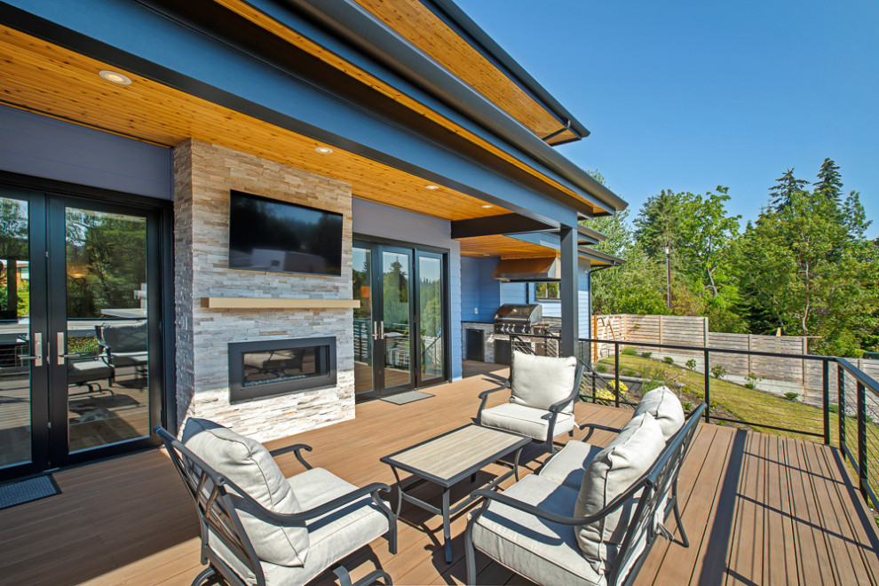 This is an example of a large traditional back wire cable railing terrace in Seattle with a roof extension and a fireplace.