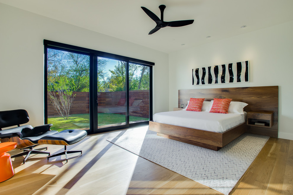 Contemporary master bedroom in Dallas with white walls and light hardwood floors.