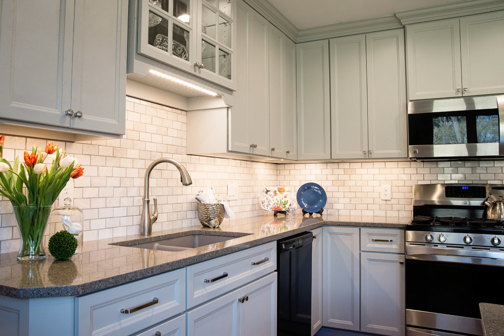 Mid-sized transitional l-shaped vinyl floor eat-in kitchen photo with an undermount sink, recessed-panel cabinets, gray cabinets, quartz countertops, white backsplash, marble backsplash, stainless steel appliances and an island