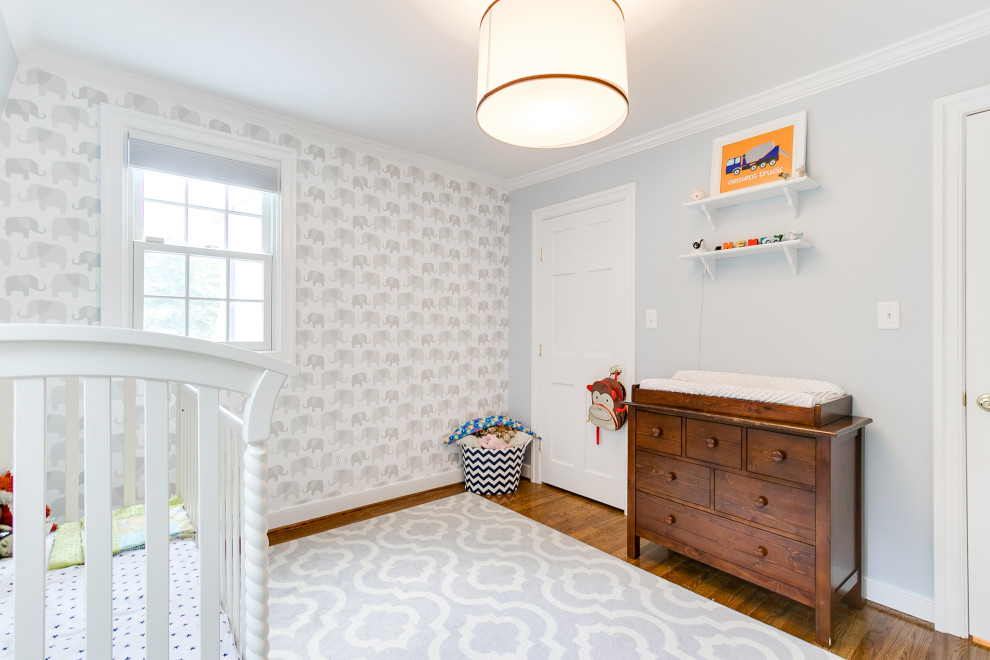 Ejemplo de habitación de bebé actual de tamaño medio con paredes blancas, suelo de madera en tonos medios y papel pintado