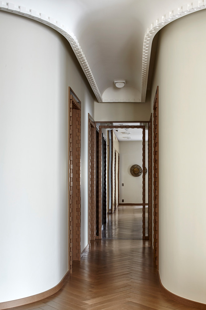 Design ideas for a contemporary hallway in Moscow with white walls, medium hardwood floors and brown floor.
