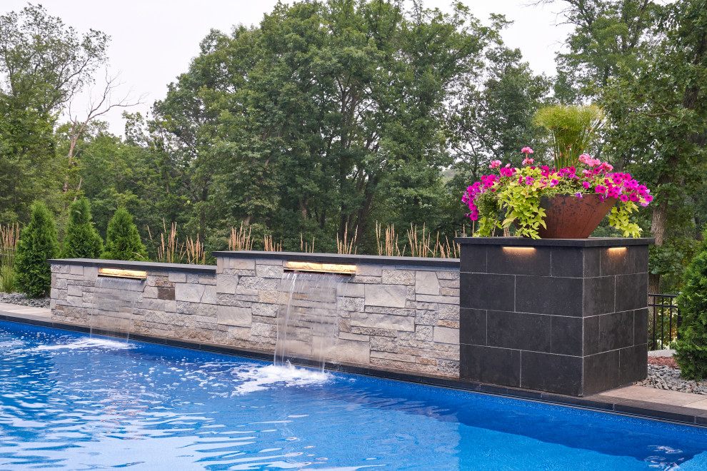 Design ideas for a large contemporary back rectangular swimming pool in Minneapolis with a water feature and natural stone paving.