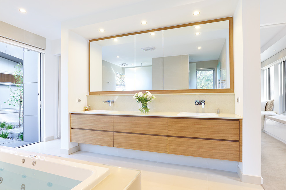 Large contemporary master bathroom in Melbourne with a drop-in sink, marble benchtops, a drop-in tub, an alcove shower, beige tile, ceramic tile, white walls, ceramic floors, medium wood cabinets and flat-panel cabinets.