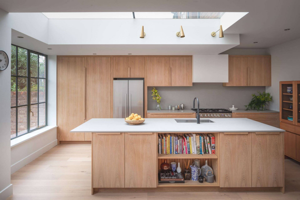 Foto på ett stort funkis vit linjärt kök och matrum, med en enkel diskho, släta luckor, skåp i mellenmörkt trä, bänkskiva i betong och en köksö