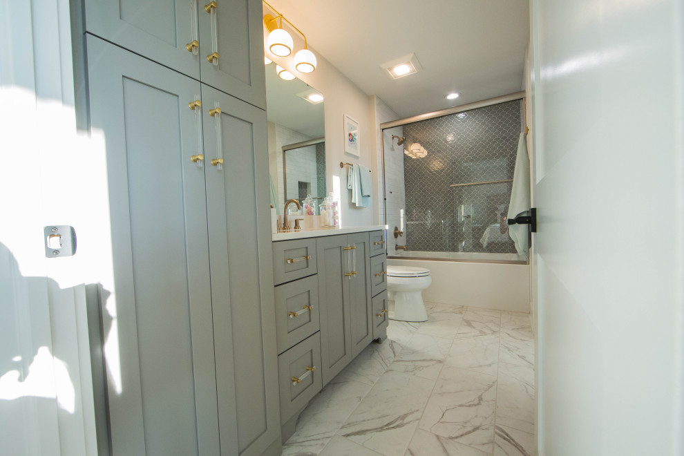 Cette image montre une très grande salle de bain minimaliste avec un placard avec porte à panneau encastré, des portes de placard grises, une baignoire posée, un combiné douche/baignoire, WC séparés, un carrelage gris, un carrelage de pierre, un mur blanc, un sol en carrelage de porcelaine, un lavabo encastré, un plan de toilette en granite, un sol blanc, une cabine de douche à porte coulissante, un plan de toilette blanc, meuble simple vasque et meuble-lavabo sur pied.