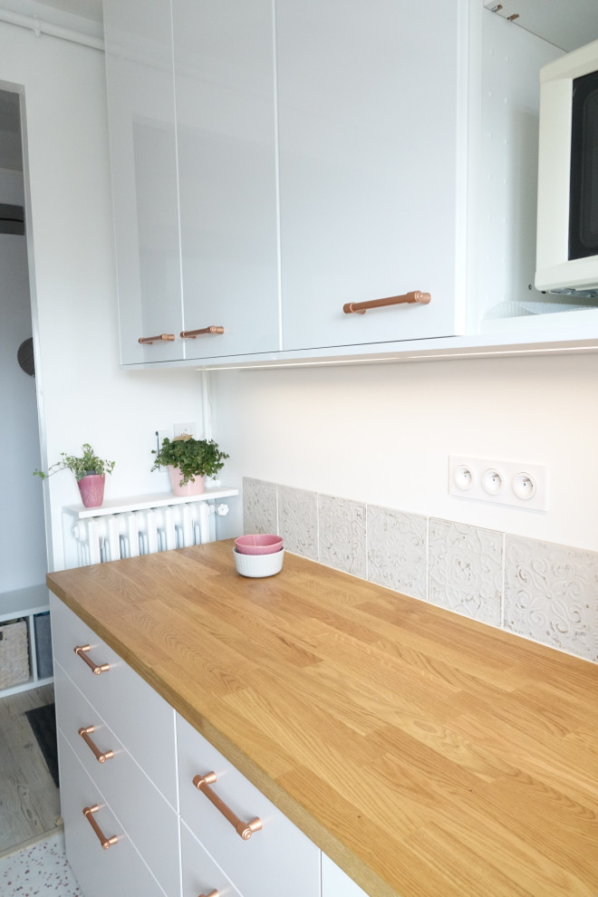 Photo of a mid-sized modern galley eat-in kitchen in Other with an undermount sink, beaded inset cabinets, pink cabinets, wood benchtops, white splashback, ceramic splashback, white appliances, terrazzo floors, a peninsula, beige floor and beige benchtop.