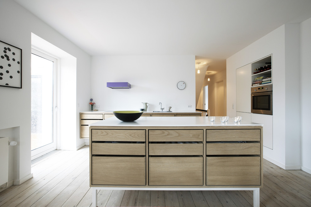 Inspiration for a modern galley eat-in kitchen in Other with an undermount sink, light wood cabinets, solid surface benchtops, white splashback and stainless steel appliances.