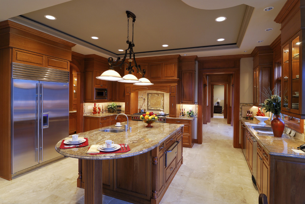 This is an example of a traditional u-shaped kitchen in Los Angeles with raised-panel cabinets, stainless steel appliances, an undermount sink, dark wood cabinets, granite benchtops, ceramic floors and with island.