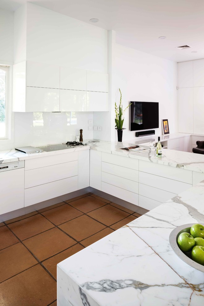 This is an example of a mid-sized modern kitchen in Melbourne with flat-panel cabinets, marble benchtops, white splashback, porcelain floors and brown floor.