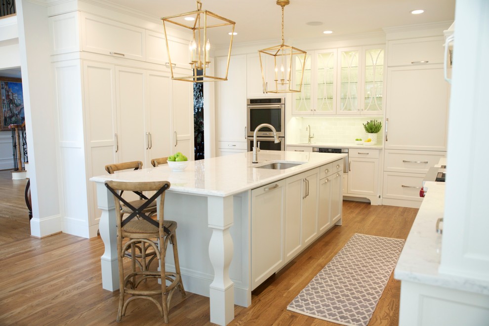 Large transitional medium tone wood floor kitchen photo in Atlanta with an undermount sink, glass-front cabinets, white cabinets, quartz countertops, gray backsplash, subway tile backsplash, paneled appliances and an island