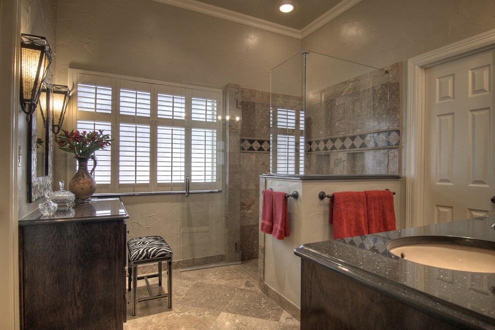 Inspiration for a mid-sized traditional master bathroom in Austin with raised-panel cabinets, an undermount sink, dark wood cabinets, granite benchtops, a corner shower, beige tile, stone tile, beige walls, travertine floors, grey floor and a hinged shower door.