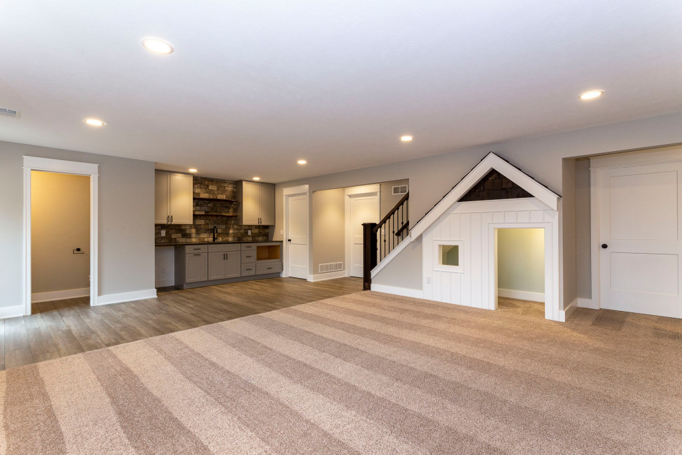 Basement - large craftsman walk-out carpeted basement idea in Grand Rapids with a bar