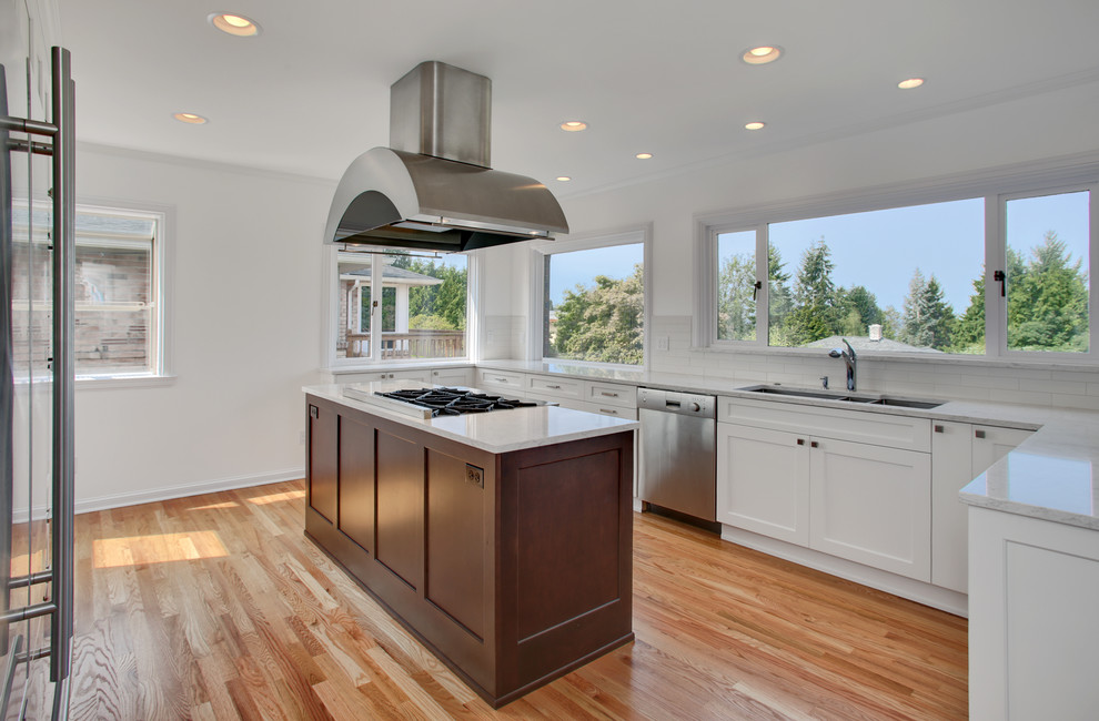 Design ideas for a mid-sized traditional eat-in kitchen in Seattle with a triple-bowl sink, shaker cabinets, white cabinets, quartzite benchtops, white splashback, porcelain splashback, stainless steel appliances, light hardwood floors and with island.