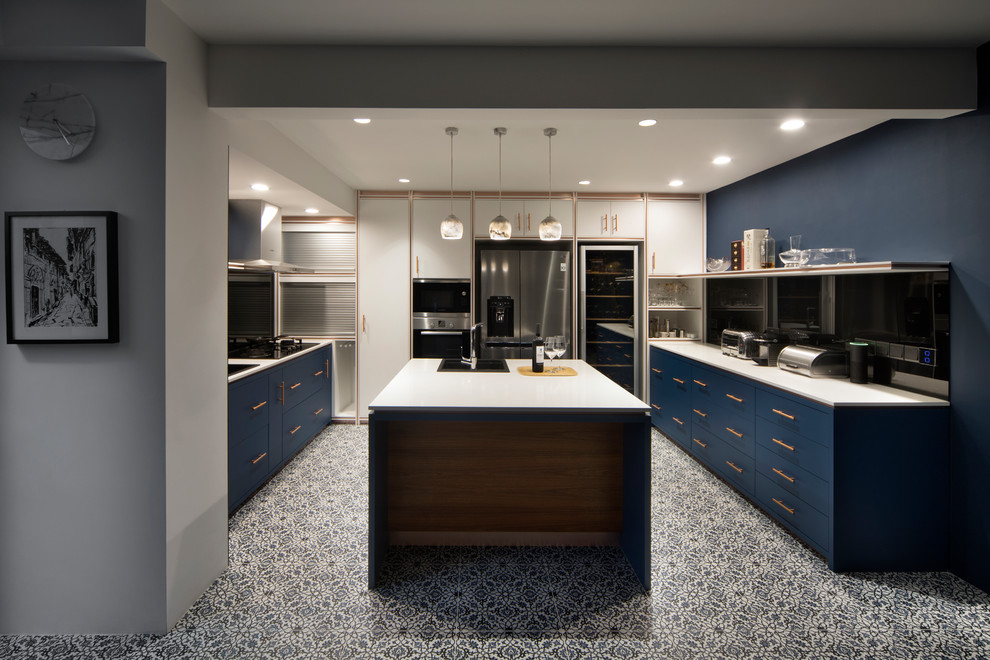 This is an example of an asian u-shaped separate kitchen in Singapore with a drop-in sink, flat-panel cabinets, blue cabinets, black splashback, glass sheet splashback, stainless steel appliances, cement tiles, with island, multi-coloured floor and white benchtop.