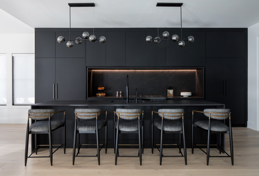 Inspiration for a large modern galley open plan kitchen in Newark with a submerged sink, flat-panel cabinets, black cabinets, black splashback, black appliances, light hardwood flooring, an island and black worktops.